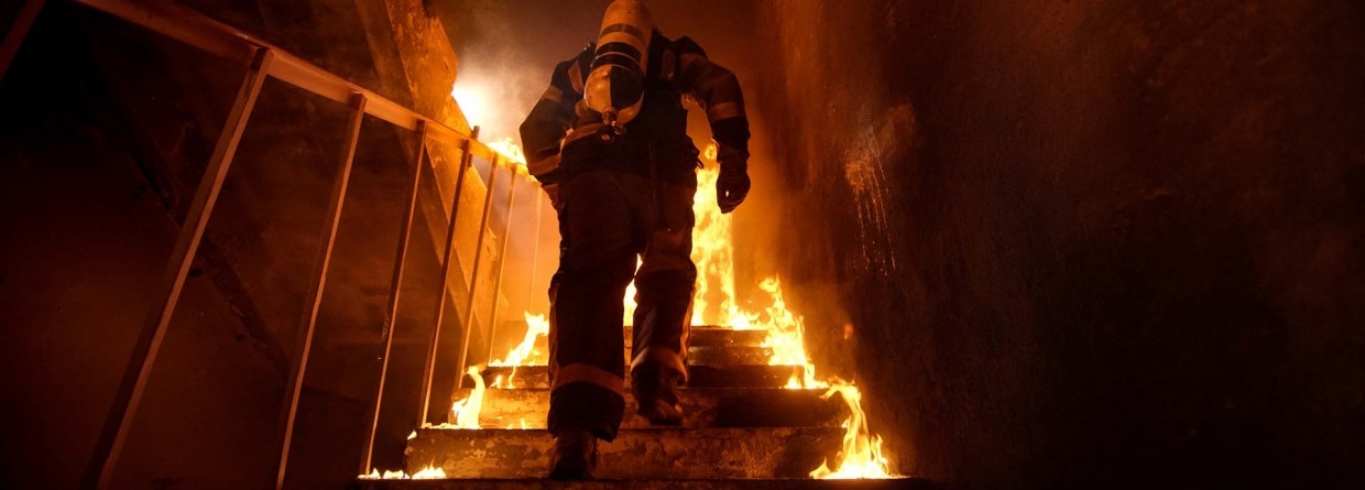 Brandweerman loopt een trap op in een gebouw waar brand is