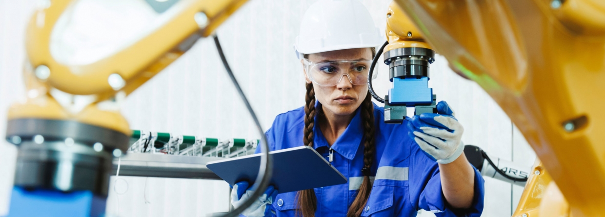 studente inspecteert robotarmmachines in een fabriekswerkplaats