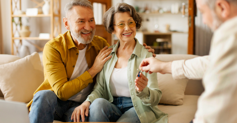 Makelaar geeft de sleutels van een woning aan een senior koppel